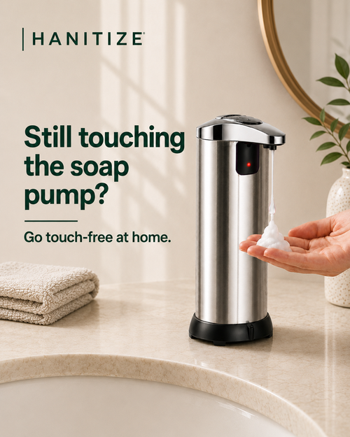 Stainless steel Hanitize automatic soap dispenser dispensing foam into a hand on a modern bathroom countertop.