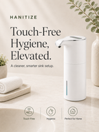 White Hanitize automatic touchless soap dispenser on a bright bathroom countertop with folded towels, plants and minimalist décor.
